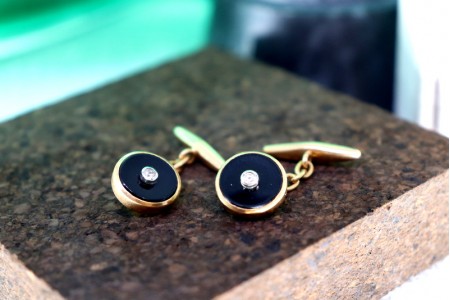 Botões de punho em ouro em formato oval com onix e zircónias no centro.